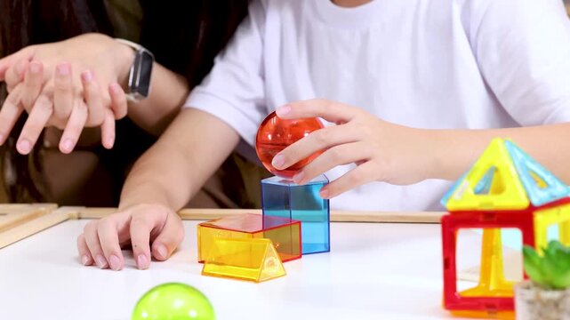 Child Stacking Colorful Blocks in Classroom with Teacher Guidance