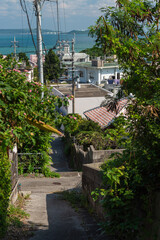 快晴の空とエメラルドグリーンの海の見える街並みと下り坂
