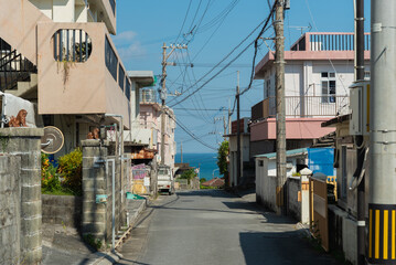 奥にエメラルドグリーンの海の見える天気の良い町の路地裏の直線道