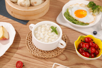 Traditional breakfast with fresh corn soup, steamed buns and fried egg on wooden table