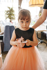 Young girl holding a toy at a cafe during the afternoon