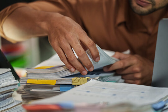 close up office employee searching and arranging documents with files and paperwork on  Desk at night