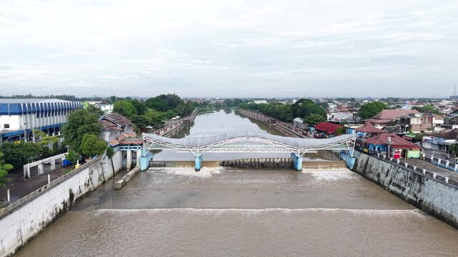 Aerial footage of the Tirtonadi Rubber Dam in Solo, Central Java, Indonesia, functions to regulate water deviation and prevent flooding of the Bewangan Solo River. High quality 4k footage