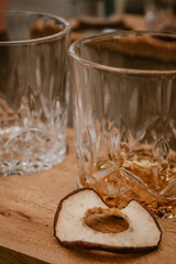 Vertical image of cocktail glasses on a wooden board with dried botanical ingredients like a peach during a gin tasting inside a restaurant.