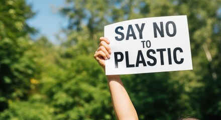 Woman holding a Say No To Plastic sign up against green trees. Environmental advocacy and activism for sustainability concept.