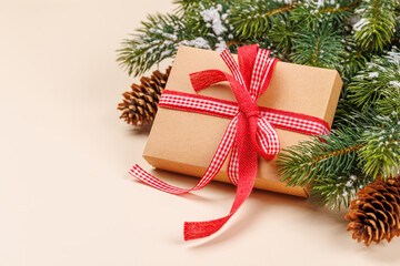 Gift box on snowy fir branches and beige background