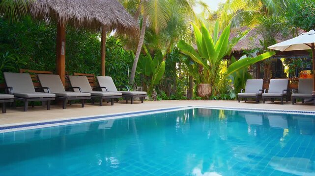 Relaxing poolside scene with lounge chairs and tropical plants.