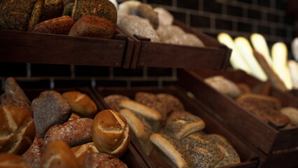 In a warm bakery, wooden shelves display a variety of freshly baked breads. Soft rolls and crusty loaves promise delightful aromas and flavors, inviting passersby to enjoy their deliciousness.