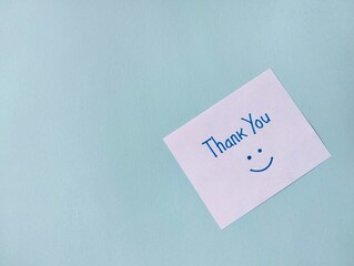 Thank you message on green note paper isolated on white background with smile emoji, Copy space	