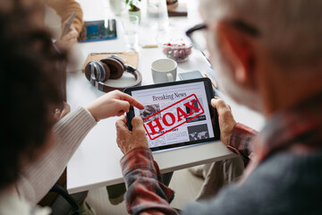 Volunteer teaching seniors how to recognize fake news on digital tablet.