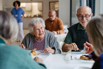 Naklejka premium Group of seniors having lunch in community center cafeteria.