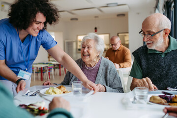 Group of seniors having lunch in community center cafeteria.