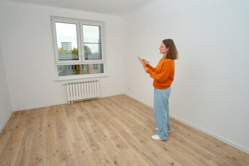 Woman inspecting new apartment, making notes on clipboard. Home inspection, new house, or real estate property management concept.