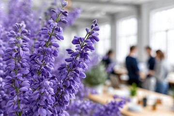 Purple Wisteria Flowers In Modern Open-Plan Office Interior. Group Of People Collaborating In Background. Creative Floral Workplace Environment