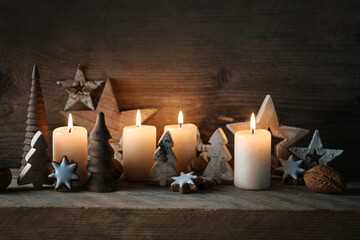 Four lit candles, natural Christmas decoration from wood and cinnamon star cookies on rustic wooden planks, Advent arrangement for the holidays, copy space, selected focus