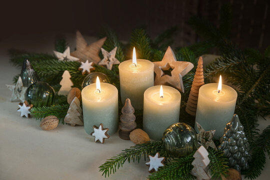 Four Advent candles, fir branches, cookies and natural Christmas decoration from glass and wood, dark background, copy space, selected focus