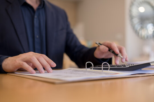 businessman calculating on calculator with document folder. Concept of finance, accounting, budget planning, tax preparation financial analysis in professional environment.