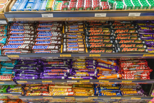 A supermarket shelf displays a variety of mints and chocolate bars, including Tic Tac, Kit Kat, Mars, Snickers and other confectionery brands