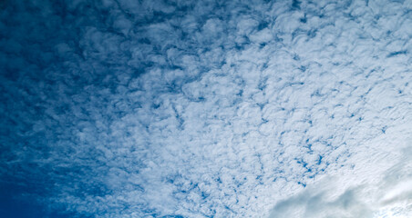 Blue sky sunset landscape with dramatic clouds lit by sunlight - colorful evening sky view, panoramic blue sky background