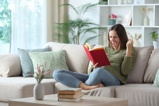 Excited woman in green reading a book at home