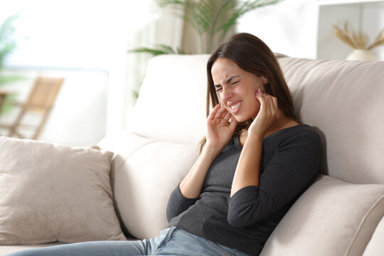 Stressed woman suffering jaw ache and complaining at home