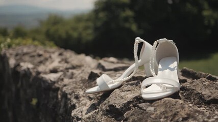 White wedding heels on stone wall in sunny outdoor setting, serene vibe