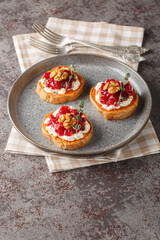 Vegetarian appetizer of baked sweet potato with cream cheese, cranberry jam, thyme and walnuts close-up in a plate on the table. Vertical