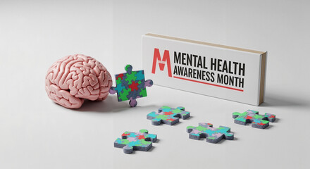 Brain model with puzzle pieces and Mental Health Awareness Month sign on a white background
