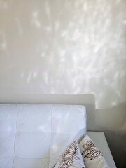 Minimalist interior scene featuring soft natural light reflections dancing on a beige wall above a white sofa. Calm, serene, and modern home aesthetic with subtle shadows and a warm, peaceful 
