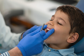 Fototapeta premium A dentist examines a boys teeth to prevent cavities and promote oral health. Regular checkups maintain strong teeth and confidence, fostering lifelong healthy habits.
