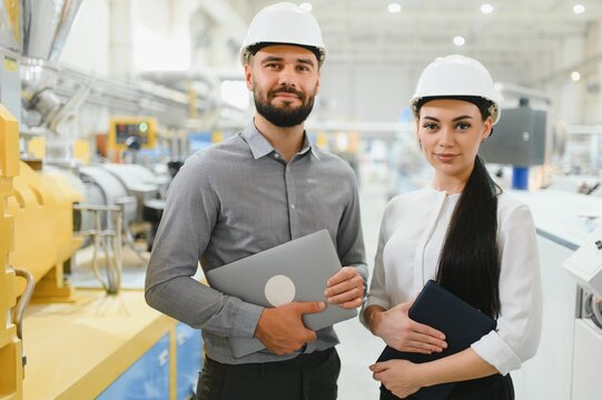Engineers holding laptops and supervising production line in factory