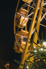 Ferris wheel at night with festive lights and Christmas tree