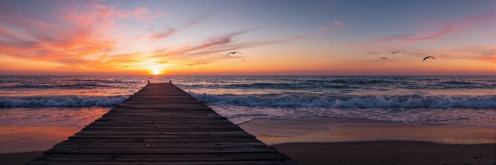 Fototapeta premium Sunset over the ocean with colorful sky, ideal for background design or visual layouts
