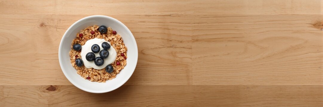 Bowl of whole grain muesli with blueberries and yogurt used as a breakfast option, health awareness day - Powered by Adobe