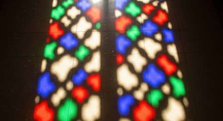 Colorful stained glass window casting vibrant light patterns on a dark surface