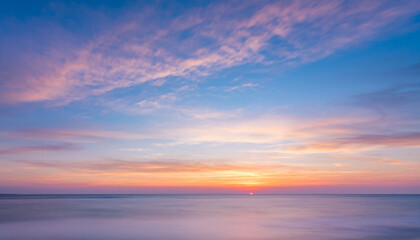 Obraz premium Ocean horizon at sunset with colorful clouds and calm water.