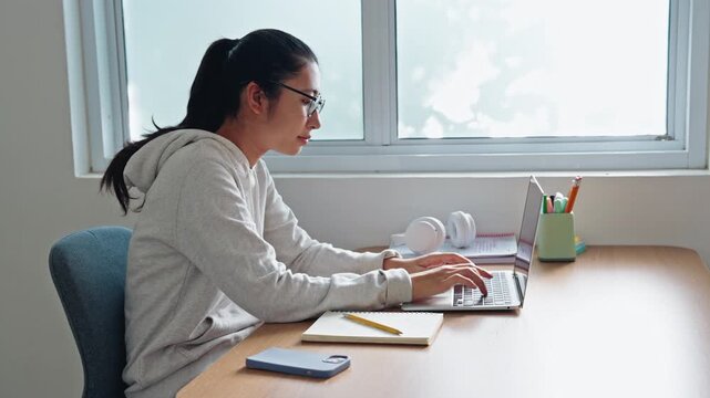 Asian girl typing work with laptop, using computer at home morning