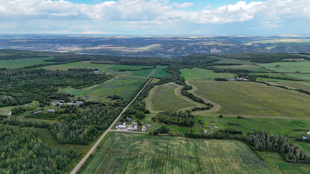 Vibrant aerial view of rolling farmland, remote homesteads, and summer skies