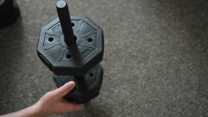 Assembling dumbbell attaching weight plates before workout. Preparing fitness equipment securing training plates for exercise. Setting up adjustable dumbbell mounting weights for upcoming sports