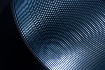 Abstract macro shot of curved metallic blue coils forming fine parallel lines on a dark background,...