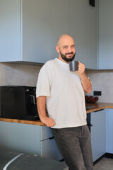 Man drinking coffee in the kitchen, leaning on the counter and enjoying a relaxed moment at home