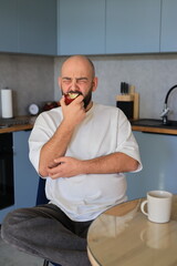 Man reacting strongly while biting into an apple, expressing an unpleasant or surprising taste...