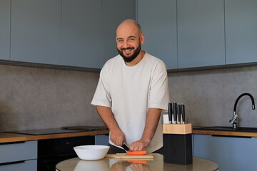 Smiling man cutting vegetables in the kitchen, enjoying a cheerful and relaxed moment during everyday cooking