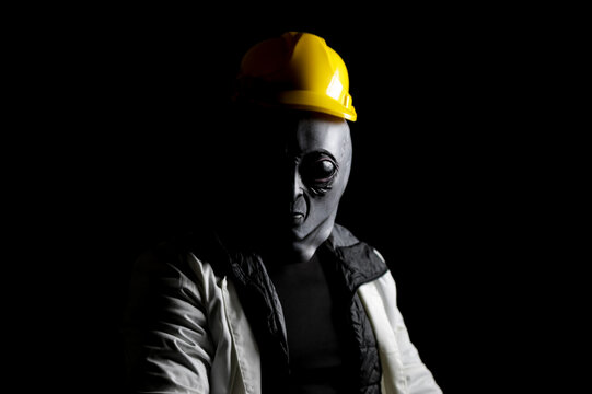 Trabajador Alien&iacute;gena con casco amarillo entre sombras