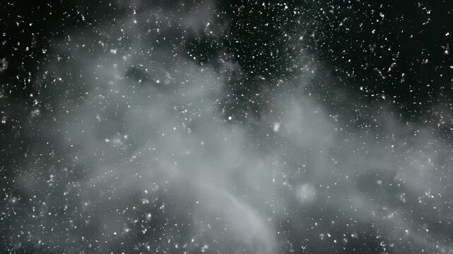 Snowboarder glides down snowy hill under dark sky surrounded by falling snow with white clouds of smoke drifting lazily across atmospheric fog shrouded landscape capturing serene winter.