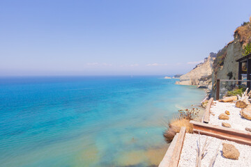 Modern cliffside balcony overlooking turquoise sea on sunny day