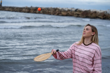 Young woman playing beach rackets by the sea
