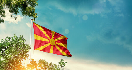 North Macedonia national flag waving in the sky behind the tree. The flag blowing with beautiful...