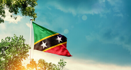 Saint Kitts and Nevis national flag waving in the sky behind the tree. The flag blowing with...