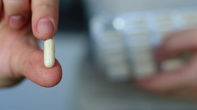 Close up of a woman holding a vitamin capsules pill, filled with granules soluble. Healthcare and wellbeing concept. 